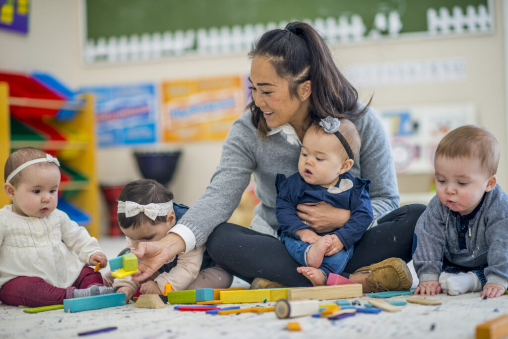 Infant teacher caring for babies in a childcare classroom, skills that translate to postpartum doula work in the Bay Area